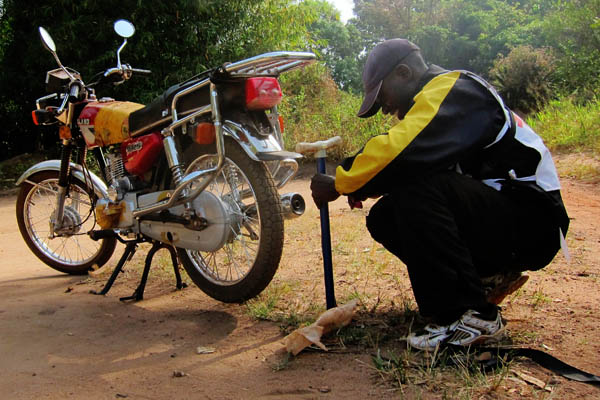Inflating a flat motorcycle tire outside Ndedu, DR Congo